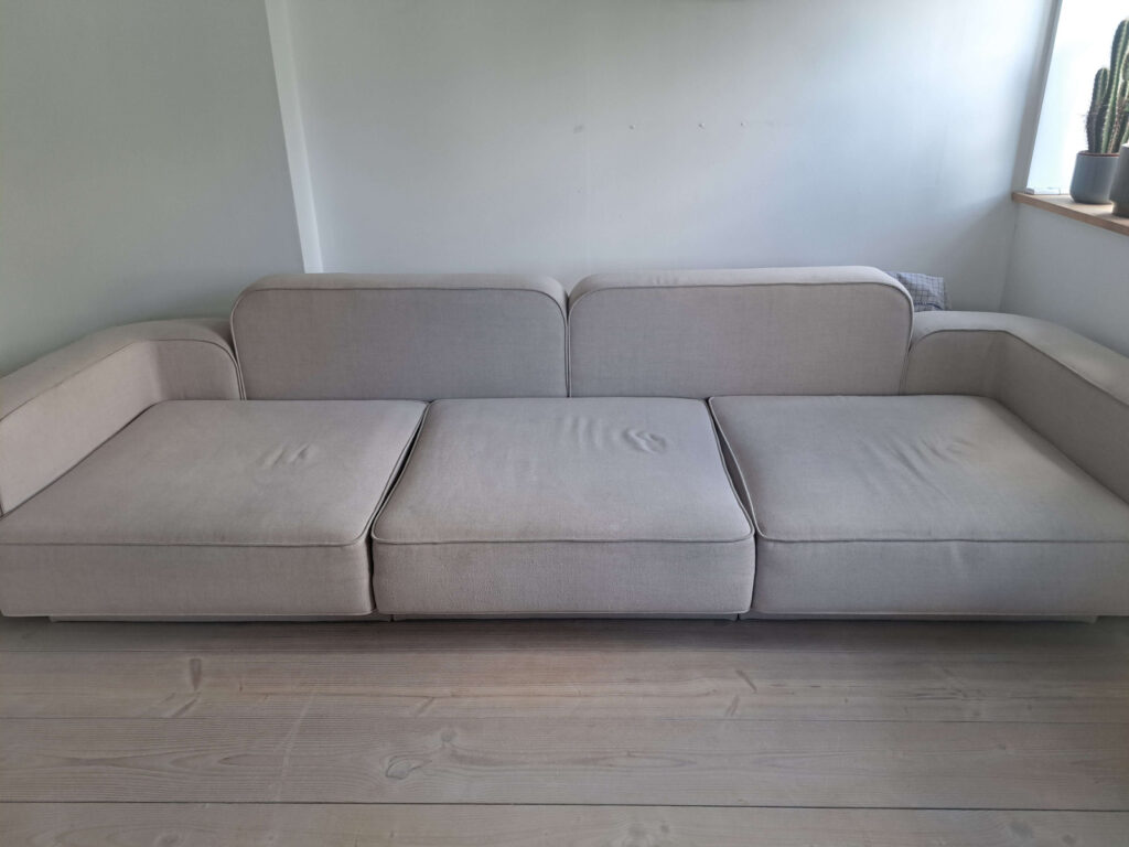 Beige sofa før rens med synlige pletter og misfarvninger